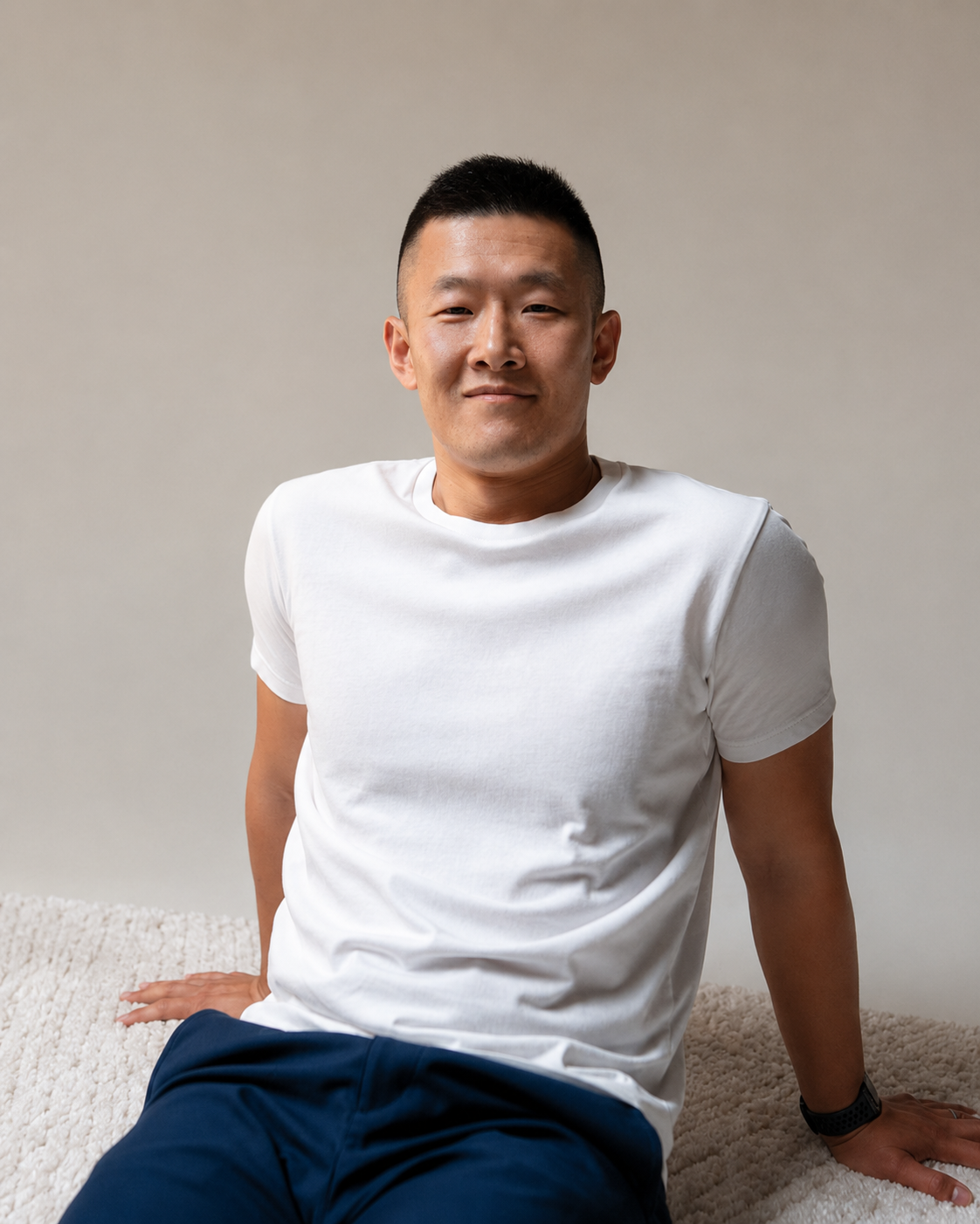 Don Chen seated casually in a warm neutral studio portrait